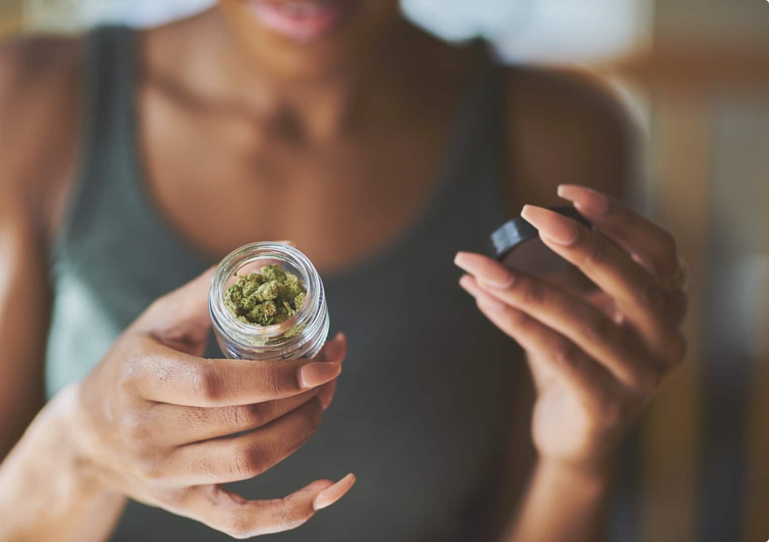 Person opening a jar of cannabis flower