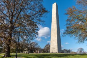 Boston, MA, USA - Nov 23, 2022: View of casual tourists visiting the Bunker Hill Monument in Boston, home to a sculpture by William H. Prescott. The Bunker Hill Monument is a monument erected at the site of the Battle of Bunker Hill in Boston, Massachusetts, which was among the first major battles between the Red Coats and the Patriots in the American Revolutionary War. In front of the obelisk is a statue of Col. William Prescott, a native of Groton, Massachusetts, another hero of Bunker Hill.